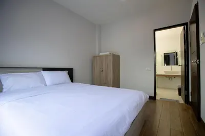 a bedroom with a large white bed and a mirror at Room 36 service apartment in Bangkok
