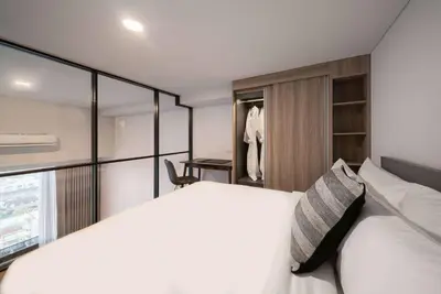 a bedroom with a white bed and a closet at Ramada By Wyndham Bangkok Sukhumvit 87 in Bangkok