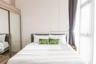 a bedroom with a large white bed with green pillows at Ramada By Wyndham Bangkok Sukhumvit 87 in Bangkok