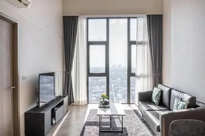 a living room with a couch and a large window at Ramada By Wyndham Bangkok Sukhumvit 87 in Bangkok