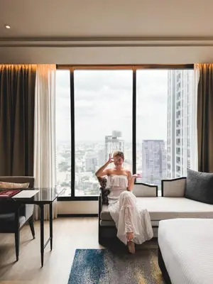 a woman sitting in a chair in a room with a window at Ascott Thonglor Bangkok in Bangkok