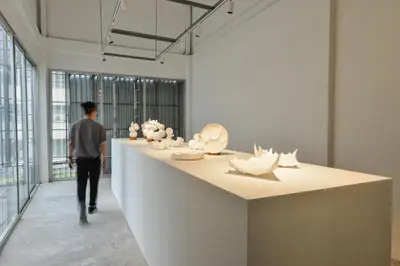 a man walking past a counter in a room with sculptures at Tiang Capsule in Bangkok