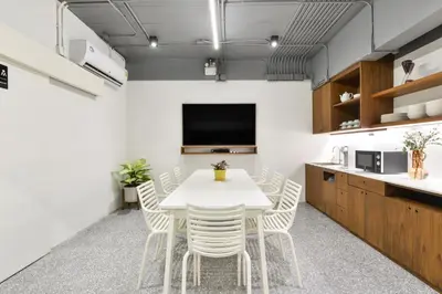 a kitchen and dining room with a white table and chairs at Tiang Capsule in Bangkok