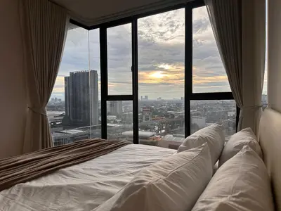 a bed in a room with a large window at Entire apartment near train station with pool & views in Ban Song Hong