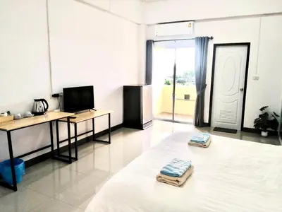 a room with a bed and a desk and a television at MY HOME Hotel - Phutthamonthon 4 Road, near Mahidol University Salaya in Ban Krathum Lom