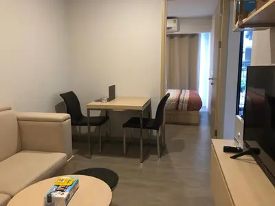 a living room with a couch and a table with chairs at SHADE of Sky Sathon - Pool, Fitness, Parking, Wifi in Bangkok