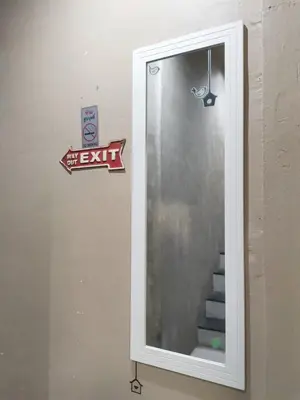 a mirror in a bathroom with a sign on the wall at Hive28 in Bang Kapi