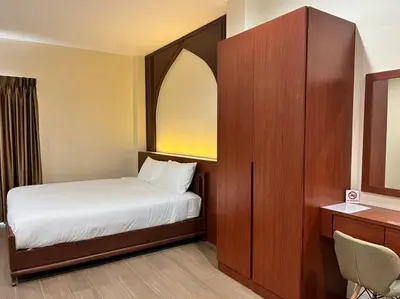a small bedroom with a bed and a mirror at Anwari Hotel in Bangkok