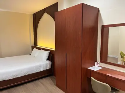 a small bedroom with a bed and a mirror at Anwari Hotel in Bangkok