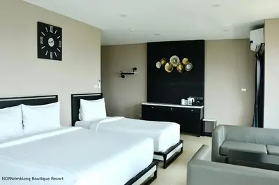 a hotel room with two beds and a chair at NORN Canalside Bangkok Hotel โรงแรมนอนริมคลอง in Bangkok Noi