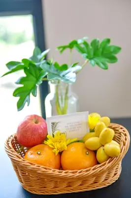 a basket of fruit on a table with a vase at NORN Canalside Bangkok Hotel โรงแรมนอนริมคลอง in Bangkok Noi