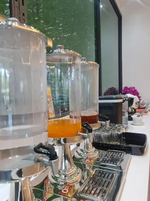 a counter with three glass vases filled with orange liquid at NORN Canalside Bangkok Hotel โรงแรมนอนริมคลอง in Bangkok Noi