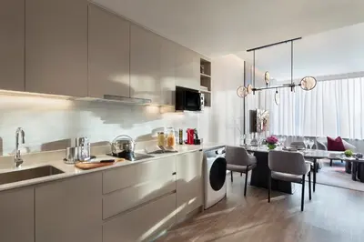 a kitchen with white cabinets and a dining room at Ascott Embassy Sathorn Bangkok in Bangkok