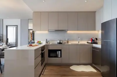 a kitchen with white cabinets and stainless steel appliances at Ascott Embassy Sathorn Bangkok in Bangkok