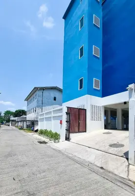 a blue building next to a parking lot at The zai Apartment in Ban Krathum Lom