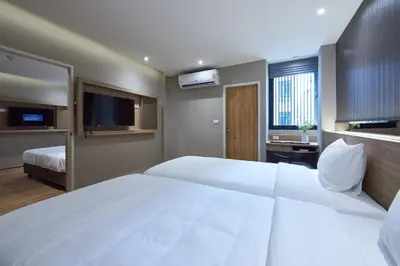 a hotel room with two beds and a flat screen tv at Almas Hotel Bangkok in Bangkok