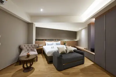 a bedroom with a bed and a couch and a chair at Almas Hotel Bangkok in Bangkok