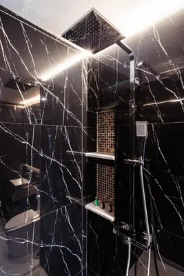 a bathroom with black marble walls and a shower at The One Smart Living in Bangkok