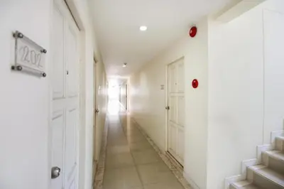 a hallway with white walls and white doors at Mee sook Hotel and Residence in Nonthaburi