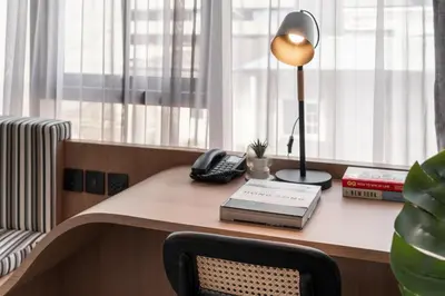 a desk with a lamp and a book on it at Seekers Finders Rama IV Hotel SureStay Collection by BW in Bangkok