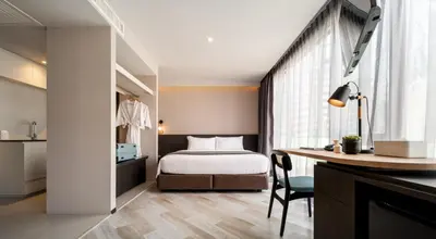 a bedroom with a bed and a desk with a chair at Seekers Finders Rama IV Hotel SureStay Collection by BW in Bangkok