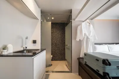 a bathroom with a bed and a sink in a room at Seekers Finders Rama IV Hotel SureStay Collection by BW in Bangkok