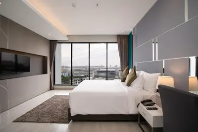 a bedroom with a large white bed and a large window at Thaya Hotel Bangkok in Bangkok