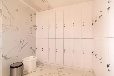 a bathroom with white cabinets and a marble wall at Thaya Hotel Bangkok in Bangkok