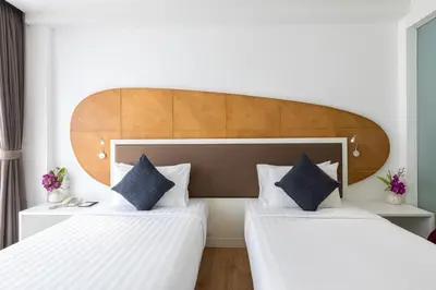 two beds in a hotel room with white and blue pillows at Hotel Icon Bangkok Sukhumvit 2 in Bangkok