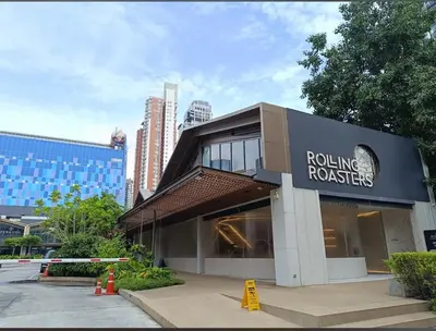 a building with a rolling roasters sign in a city at Nato house Ekkamai in Bangkok