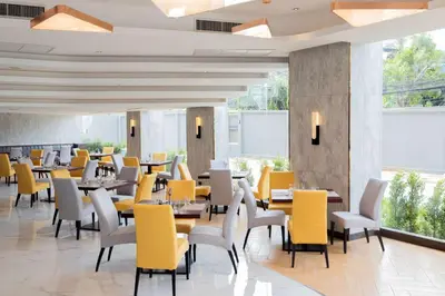 a restaurant with tables and chairs and yellow chairs at Best Western Nada Don Mueang Airport hotel in Bangkok