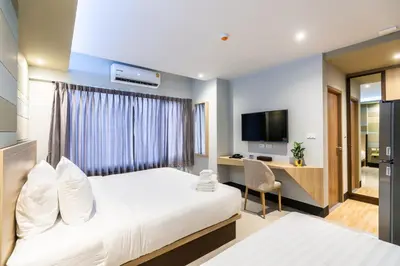 a bedroom with a bed and a desk and a television at Hi Sotel Victory Monument in Bangkok