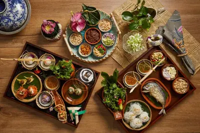 a table with plates of food and bowls of food at The Salil Hotel Riverside Bangkok in Bangkok