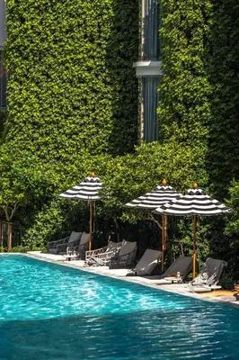 a swimming pool with umbrellas and lounge chairs and a swimming pool at The Salil Hotel Riverside Bangkok in Bangkok