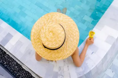 a person wearing a straw hat sitting in a swimming pool at The Salil Hotel Riverside Bangkok in Bangkok