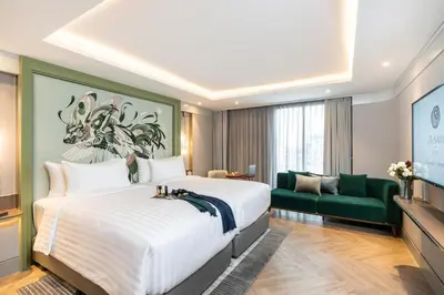 a hotel room with a large bed and a green couch at The Salil Hotel Riverside Bangkok in Bangkok