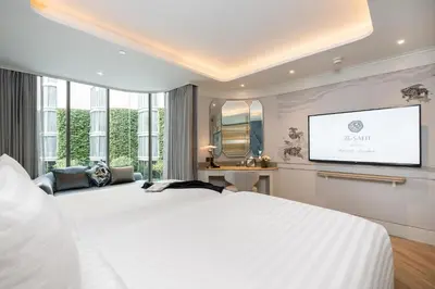 a bedroom with a white bed and a flat screen tv at The Salil Hotel Riverside Bangkok in Bangkok
