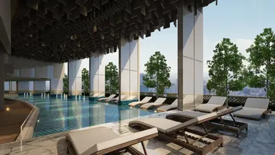 a swimming pool with lounge chairs in a building at Oakwood Suites Tiwanon Bangkok in Nonthaburi