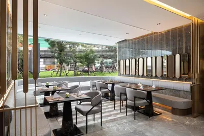 a restaurant with tables and chairs and a wall with mirrors at Oakwood Suites Tiwanon Bangkok in Nonthaburi