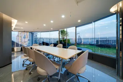a conference room with a table and chairs and large windows at Oakwood Suites Tiwanon Bangkok in Nonthaburi