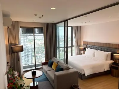 a hotel room with a bed and a couch at Oakwood Suites Tiwanon Bangkok in Nonthaburi