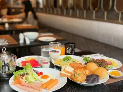 a table with plates of food and glasses of wine at Oakwood Suites Tiwanon Bangkok in Nonthaburi
