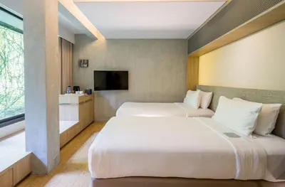 a hotel room with two beds and a television at Ad Lib Hotel Bangkok in Bangkok