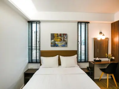 a bedroom with a large white bed and a desk at Kitzio House Hotel Huai Kwang in Bangkok