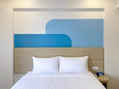 a bed with white sheets and a blue headboard at HOP INN Bangkok Onnut Station in Bangkok