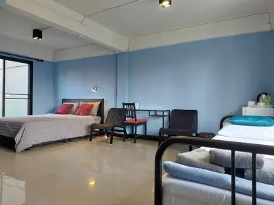 a bedroom with two beds and chairs and blue walls at HOUSEMODE - BAANYAI @ Wongwian Yai in Bangkok