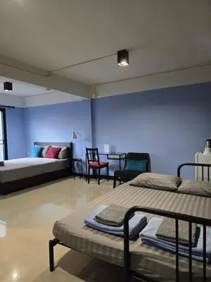 a room with two beds and a table and chairs at HOUSEMODE - BAANYAI @ Wongwian Yai in Bangkok