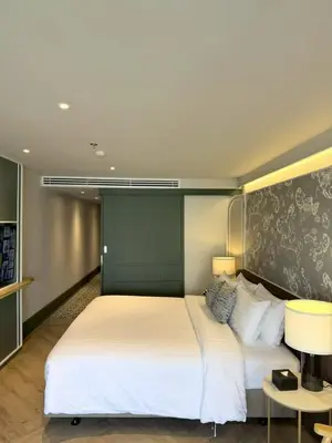 a bedroom with a large white bed with a green headboard at The Quarter Chaophraya by UHG in Bangkok