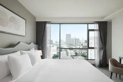 a bedroom with a white bed and a large window at Livable Hotel Bangkok in Bangkok