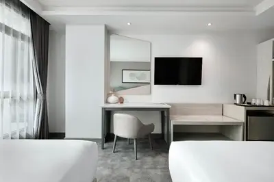 a white room with a desk and a television at Livable Hotel Bangkok in Bangkok